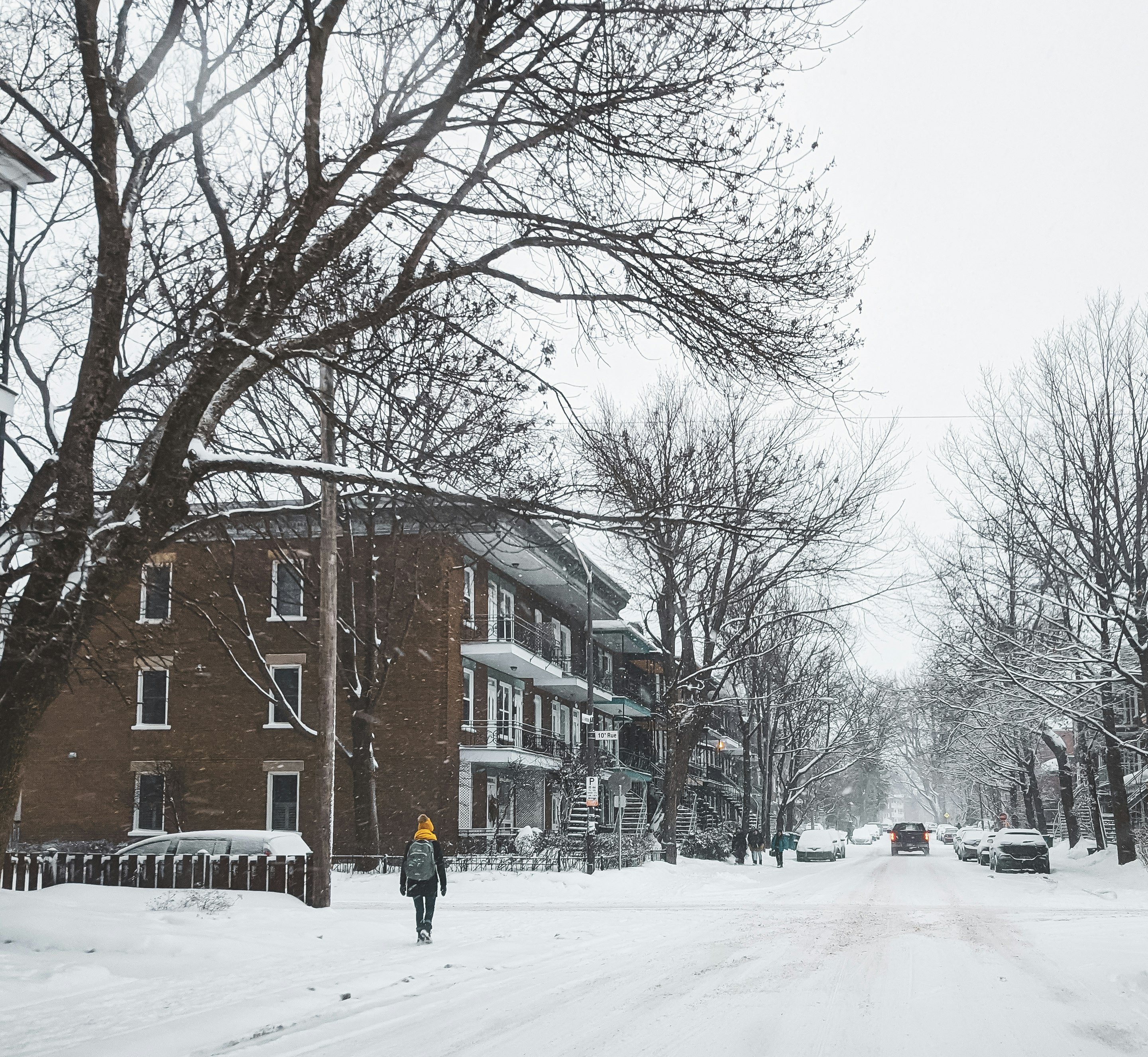 person in black jacket walking on snow covered road during daytime